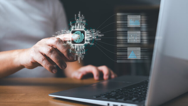 Biometric fingerprint scan and cybersecurity access concept. Man scanning finger on digital futuristic interface with data analytics charts while using laptop computer at office desk.