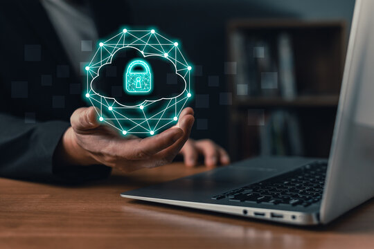 Secure cloud computing and data security concept. Businessman using a laptop while holding a glowing digital cloud and computer network security icon in hand. storage technology in business.