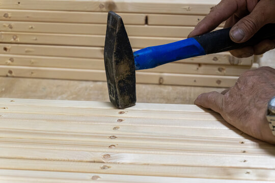 Carpenter hammering wooden dowel pin into wooden plank in workshop
