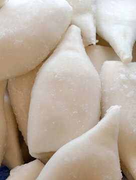 Clean white squid pieces stored frozen in a supermarket refrigerator, fresh seafood product suitable for cooking and meal preparation