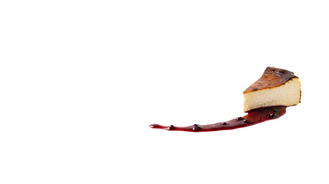 Small slice of creamy Basque burnt cheesecake served with a line of dark red berry fruit sauce drizzle isolated on transparent background. 