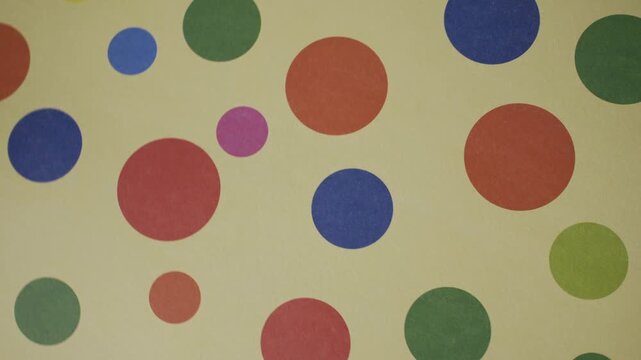 Panning shot of colorful polka dot pattern with various shapes on a yellow background