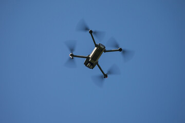 Drone flying against a clear blue sky viewed from below © Viacheslav Zhukov