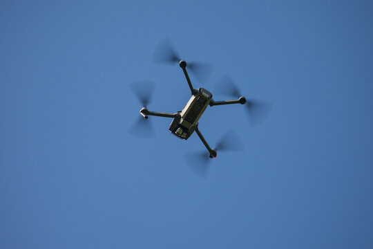 Drone flying against a clear blue sky viewed from below