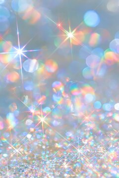 Dreamy iridescent rainbow bokeh with sparkling starbursts and a translucent bubble on a soft blue background, vertical abstract magical backdrop with copy space