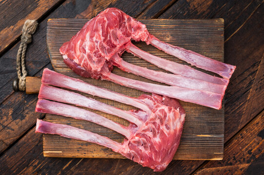 Raw lamb rack ribs with bone on rustic wooden board dark background top view butcher style meat with copy space
