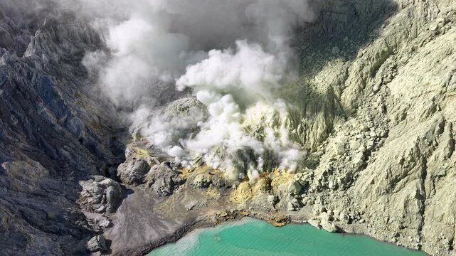 Steam rises from volcanic crater, swirling through rocky walls at Mount Ijen