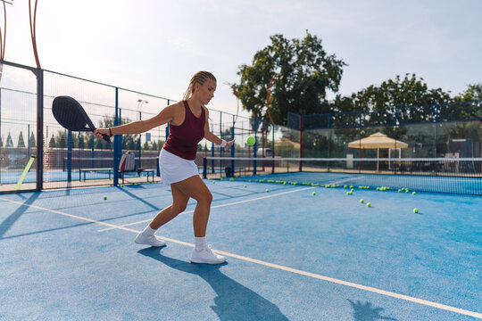 Female player having paddle tennis training on outdoor court.