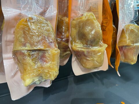 Close-up view of hocks individually vacuum sealed in clear plastic packs and arranged for retail display. Food for dogs and pets.