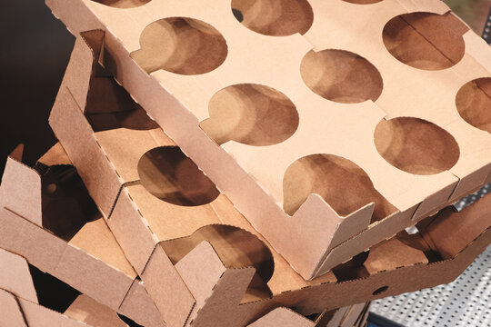 Elements of corton boxes collected in stack. Conveyor line for production of boxes. Machine cuts cardboard boxes from sheets of cardboard. Enterprise for production package.