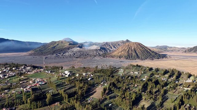 Mount Bromo crater glows under clear skies. Villages nestle beside rugged volcanic slopes