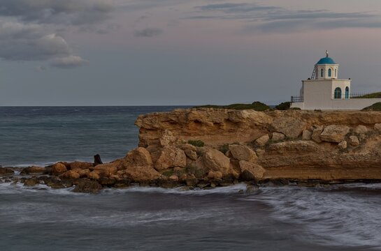 Agia Paraskevi chapel overlooking the rocky coast and evening sea, Artemida, Greece