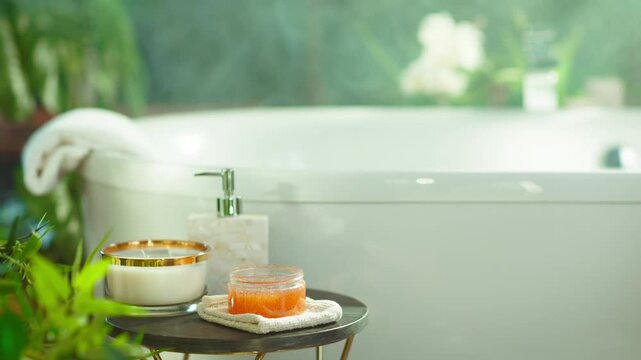Luxurious, spa-like bathroom setting for relaxation & self-care. White bathtub visible. Round side table holds candle, scrub jar, & soap dispenser, accented by soft lighting & green plants.
