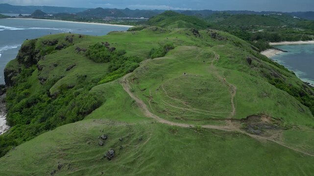 High Drone View Curved Turquoise Bay And Reef With Visible Coral Formations, Crescent White Beach, Emerald Hills And Shallow Lagoon Pools Bright Midday Light, Bukit Merese, Lombok, Tanjung Ann beach