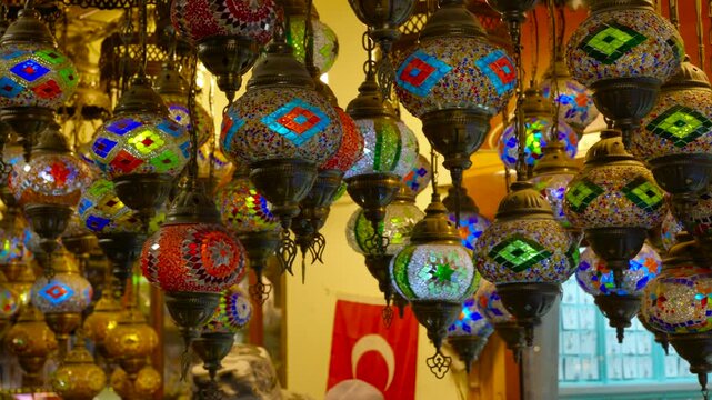 Colorful handmade turkish mosaic lamps gently swinging in a traditional souvenir shop, with a turkish flag visible in the background creating an authentic atmosphere
