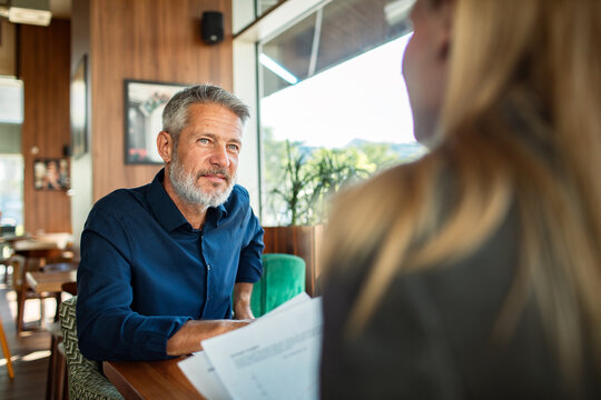 Mature man listening during meeting in cafe
