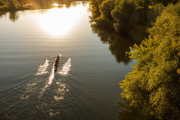 Rowing team moves across river at sunset © Iryna Miadzvedzeva