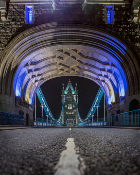 Middle of the road surface level view of Tower bridge illuminated at night, London, England, UK