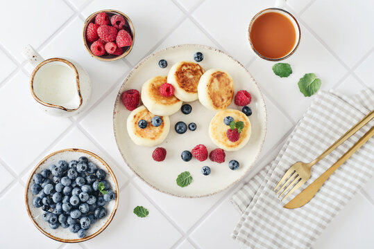 Cottage cheese pancakes with fresh blueberries, raspberries and mint on a plate