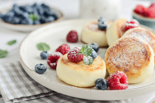 Cottage cheese pancakes with fresh blueberries, raspberries and mint on a plate