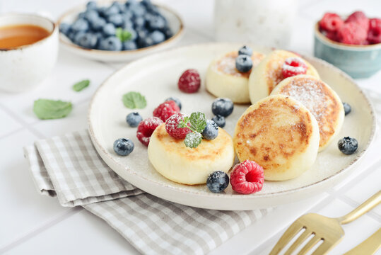 Cottage cheese pancakes with fresh blueberries, raspberries and mint on a plate