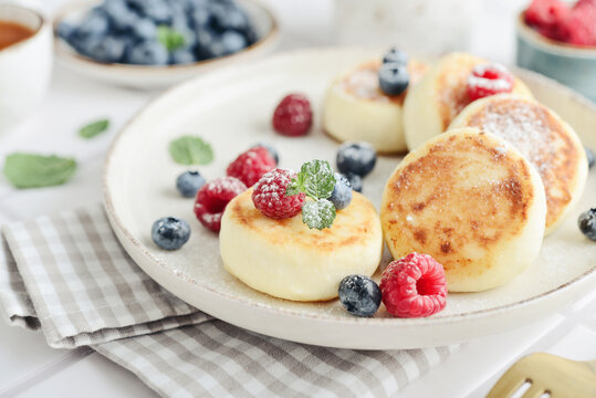 Cottage cheese pancakes with fresh blueberries, raspberries and mint on a plate