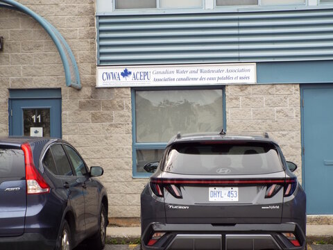 Gloucester, Ontario, Canada &ndash; July 31, 2026: The "Canadian Water and Wastewater Association" storefront sign is displayed above a window on a commercial building exterior with parked cars at 1010 Poly