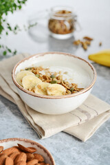 Greek yogurt with muesli and sliced banana in a bowl on a marble countertop © tashka2000