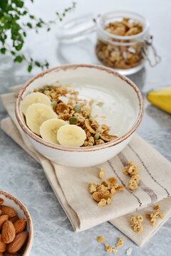Greek yogurt with muesli and sliced banana in a bowl on a marble countertop