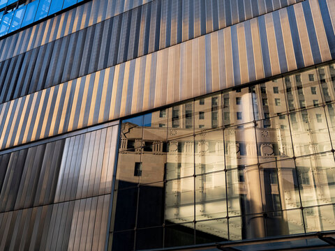 New York City, New York &ndash; October 3, 2026: Metal louvers and a glass curtain wall on the exterior of an office building in Lower Manhattan, with a reflection of a stone building in the glass.
