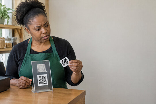 Shop Worker Removes a Fake QR Payment Sticker from a Counter Display After Spotting a Payment Redirection Scam