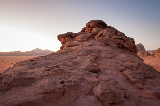 Red sandstone rock formation in a desert landscape at sunset