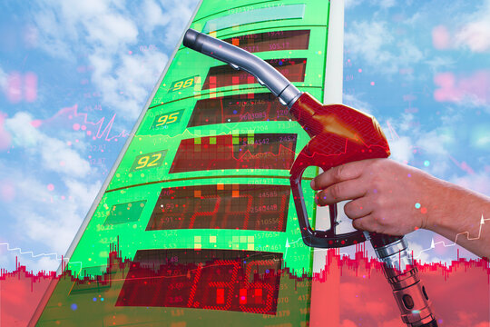 Hand holding red fuel nozzle over gas station totem with stock trading chart double exposure. Energy crisis, rising gasoline price, oil commodity market trading and inflation concept.
