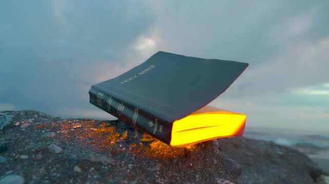 Holy Bible on Rocky Beach with Glowing Golden Light