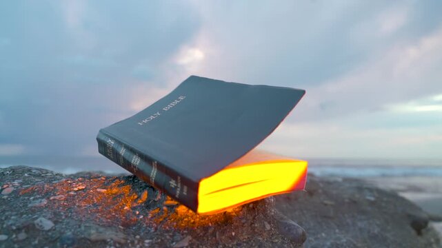 Holy Bible on Rocky Beach with Glowing Golden Light