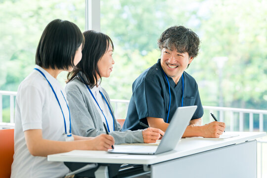 笑顔で意見交換する医師と女性看護師。病院でのミーティングとチーム医療の風景
