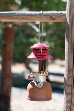 Vintage Rusted Red Camping Lantern Hanging From Wooden Post