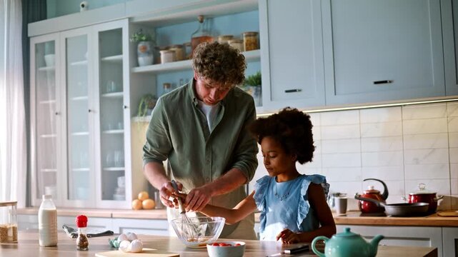 Little girl whisking eggs father kitchen. Family preparing breakfast morning.
