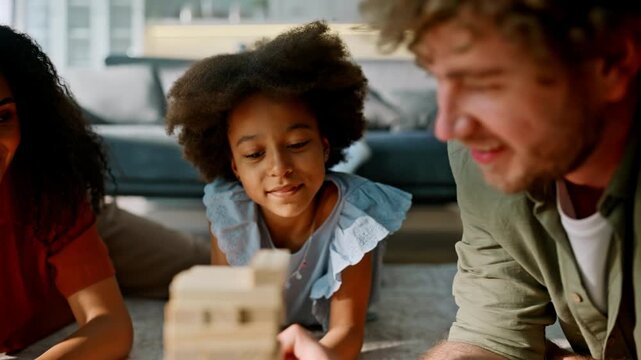 Closeup wooden blocks tower game family floor. Girl father mother playing home.