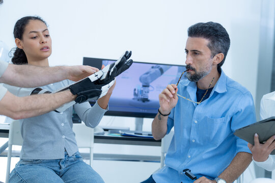 Robot arm ergonomics study: a researcher extends her full bionic arm straight out across the bench, holding it level so the load on the shoulder can be assessed