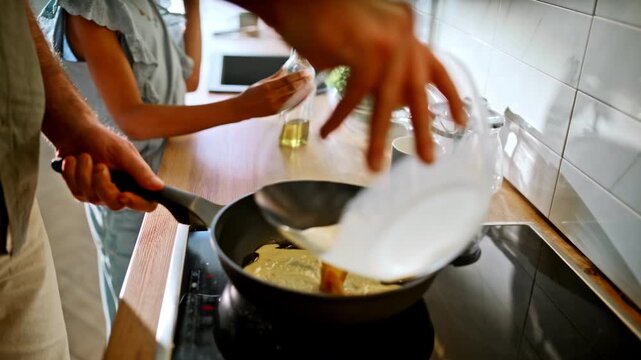 Dad cooking omelette pan kitchen. Multiracial child helping prepare breakfast.
