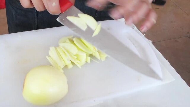 Hand knife cut and slice fresh apple fruit on white board table 