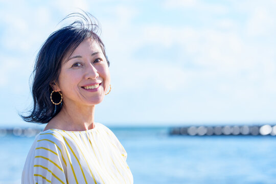 海辺に立つ笑顔のシニア女性