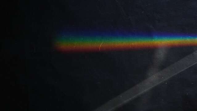 Rainbow light prism refraction on a dark black textured background