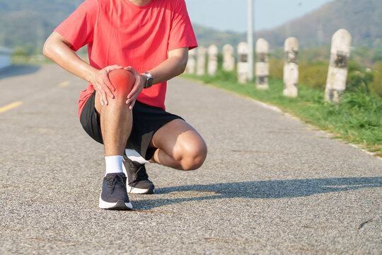 Young adult male runner with knee pain from ACL injury or patellofemoral syndrome. Man having joint ache, ligament tear or patellar tendinitis during running. Sports medical and healthcare concept