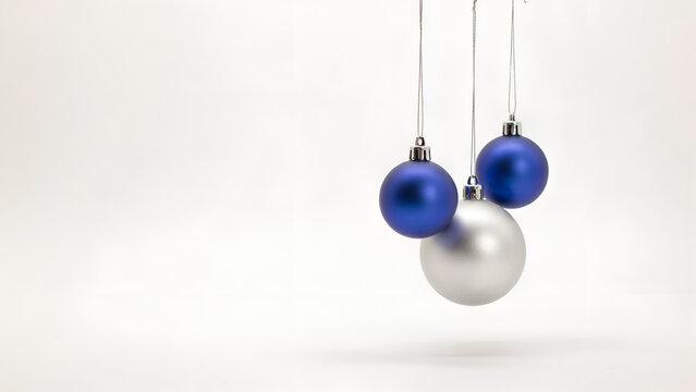 Three blue and silver christmas baubles hanging against a white background isolated on white background