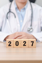 Fototapeta premium Happy New Year 2027 with Stethoscope of doctor and heart shape on table. health care, Insurance, Wellness and medical concepts