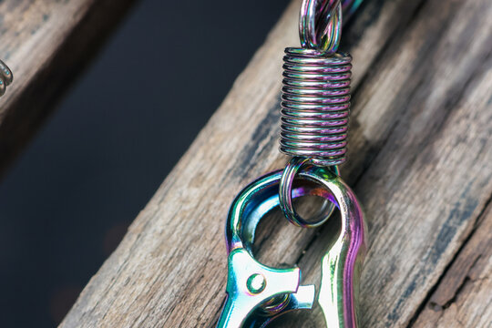 Metallic fishing hook with coiled wire, polished clasp, and colorful reflection resting on weathered wooden surface, creating rugged outdoor angling detail