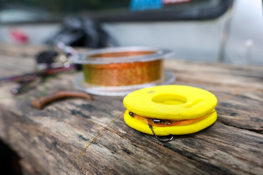 Yellow fishing reel and copper wire spool on weathered wooden workbench