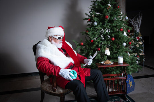 Santa reviewing naughty and nice list beside Christmas tree
